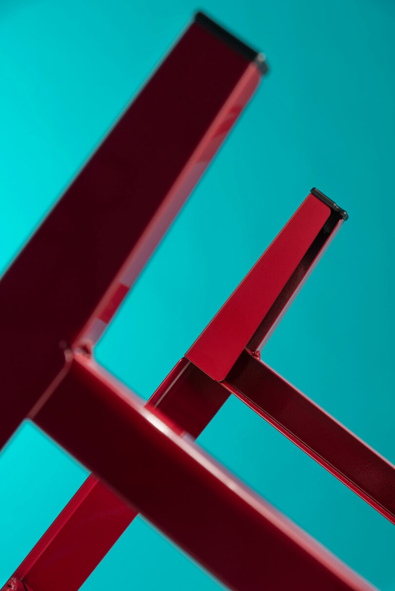 Close-up of red metal chair legs emphasizing the high-gloss finish and clean lines.