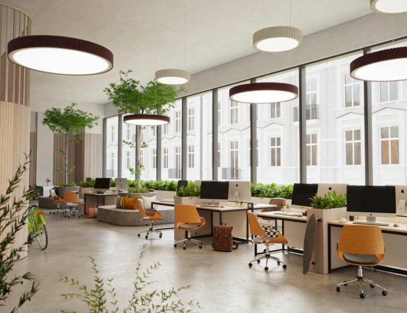 Modern open-plan office with circular ceiling lights, wooden desks, and orange chairs.