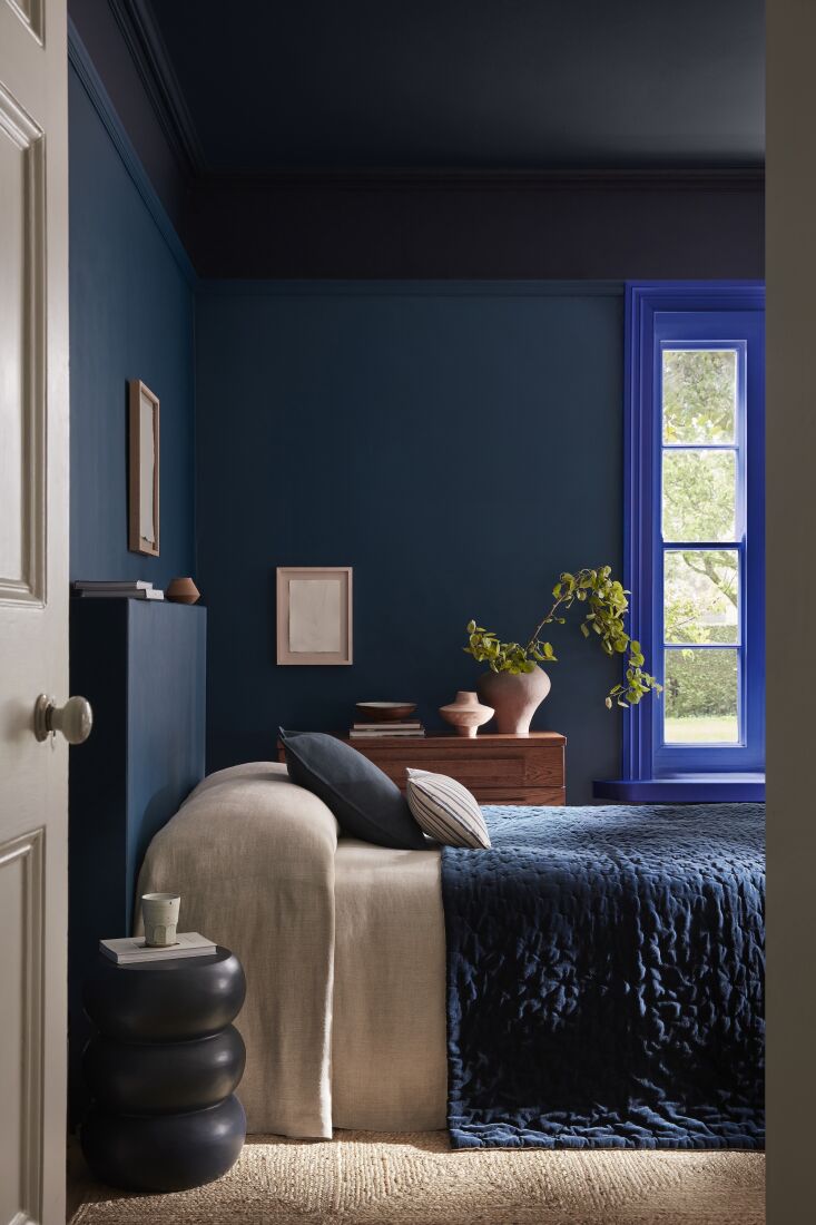 A close-up of a bedroom corner showing different blue paint shades on the wall and architectural trim.