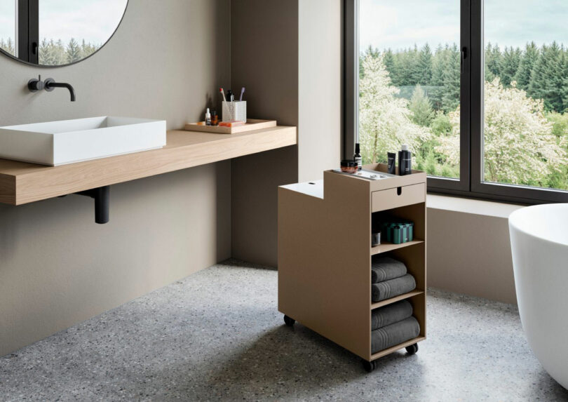 A storage cart organized with towels and toiletries in a modern bathroom setting.