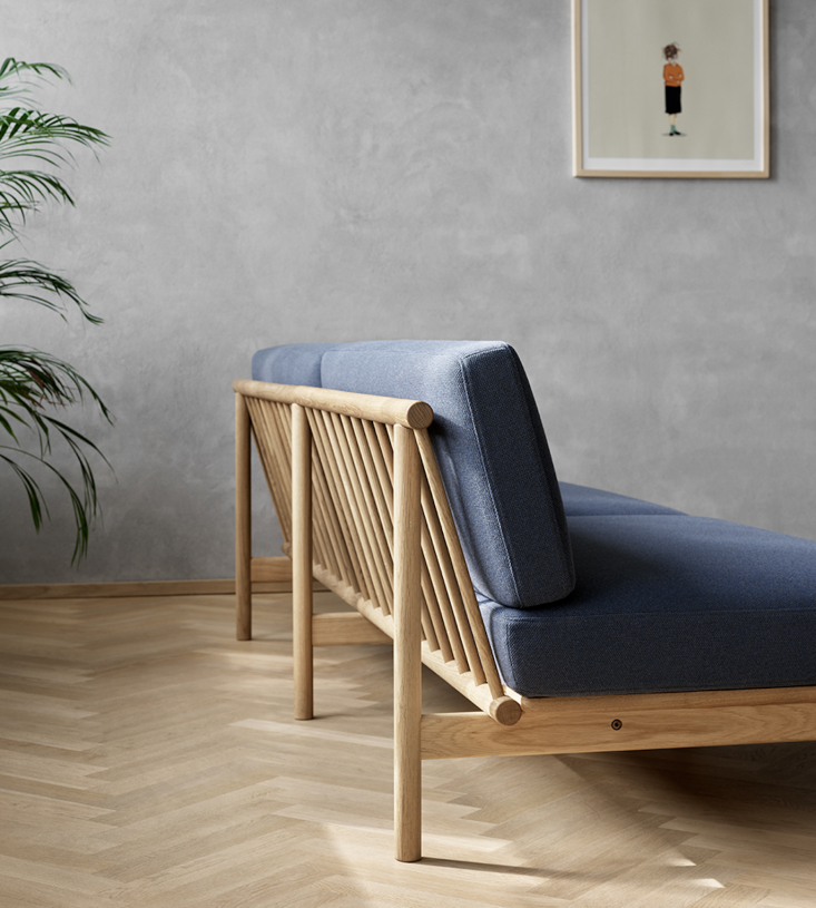 The Spoke Sofa featuring the Oak Golden Oil finish and grey upholstery.
