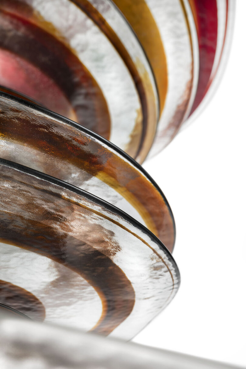 Close-up of textured Murano glass plates with swirling patterns in amber and red.