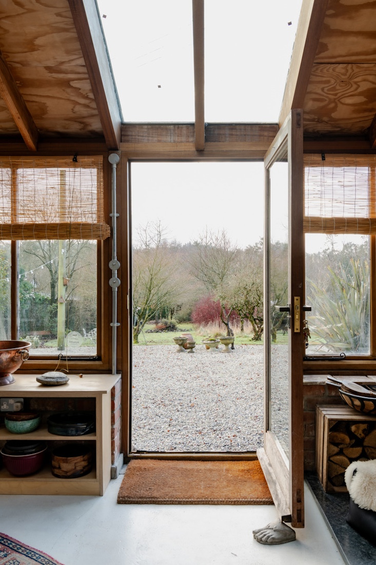 View from the open front door looking out onto a gravel terrace and green landscape.