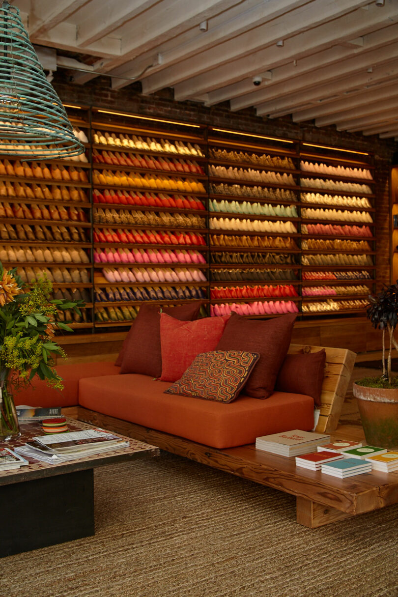 A cozy seating area with vibrant cushions in front of a wall of colorful hand-stitched leather shoes.