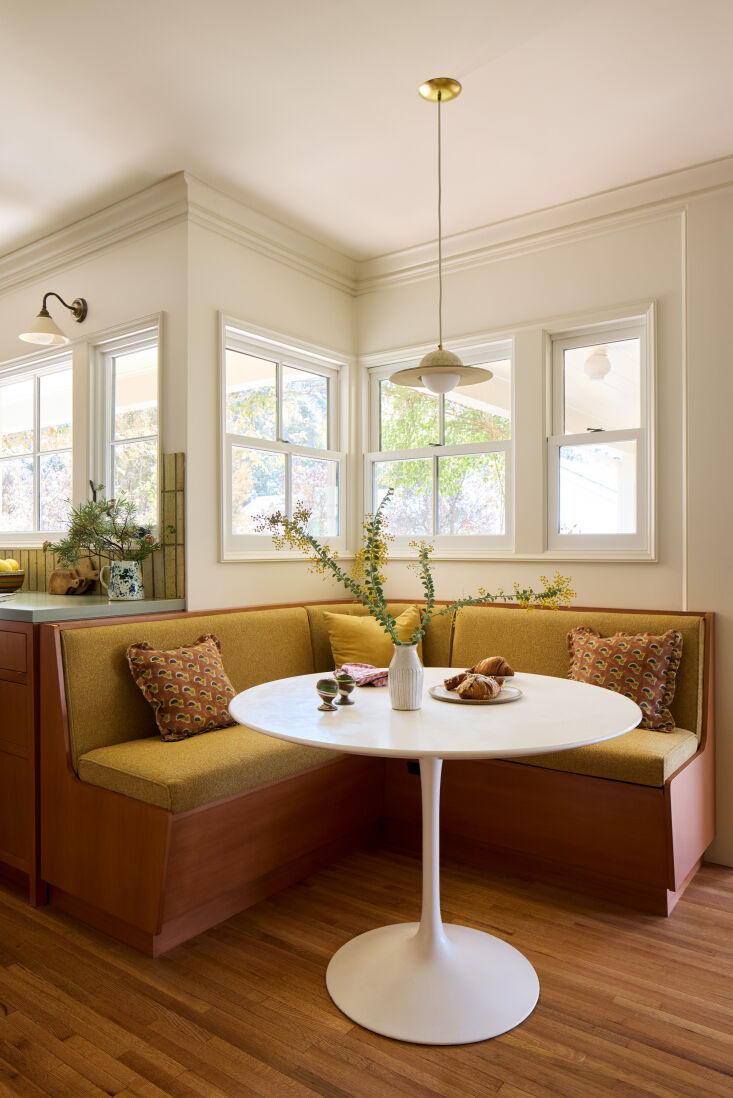 A yellow upholstered custom banquette with a built-in drawer for board games.