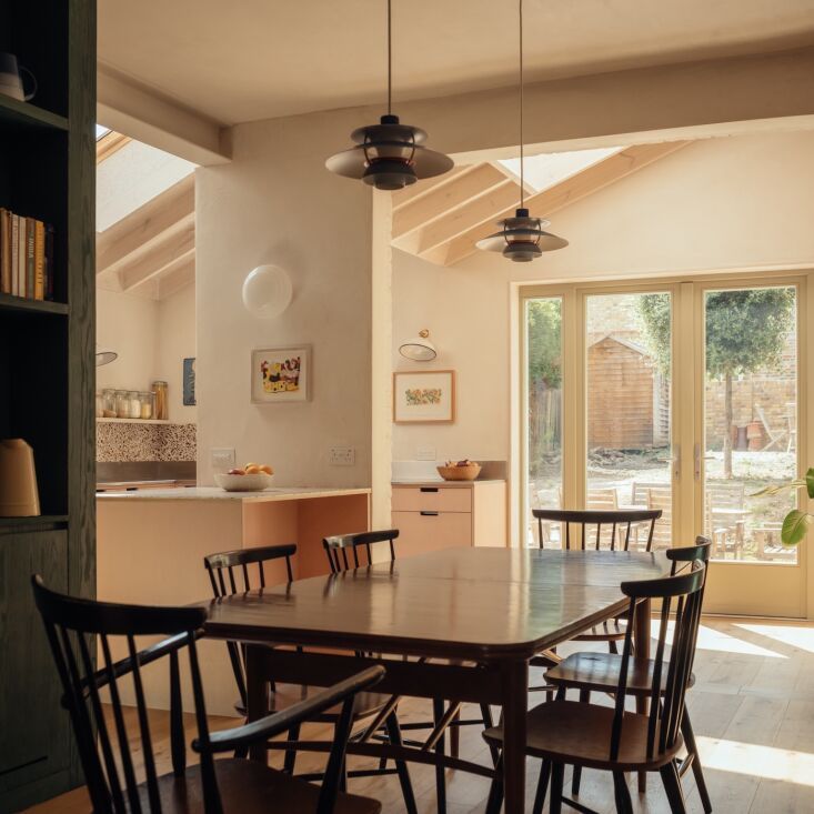 A bright, modern kitchen with skylights, plywood cabinetry, and wide-plank flooring.