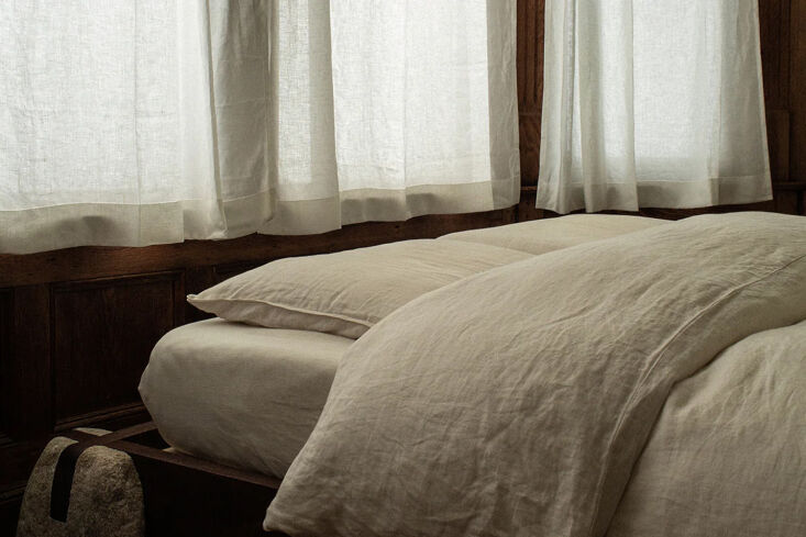 Light-colored chalk white linen fitted sheet on a minimalist bed.