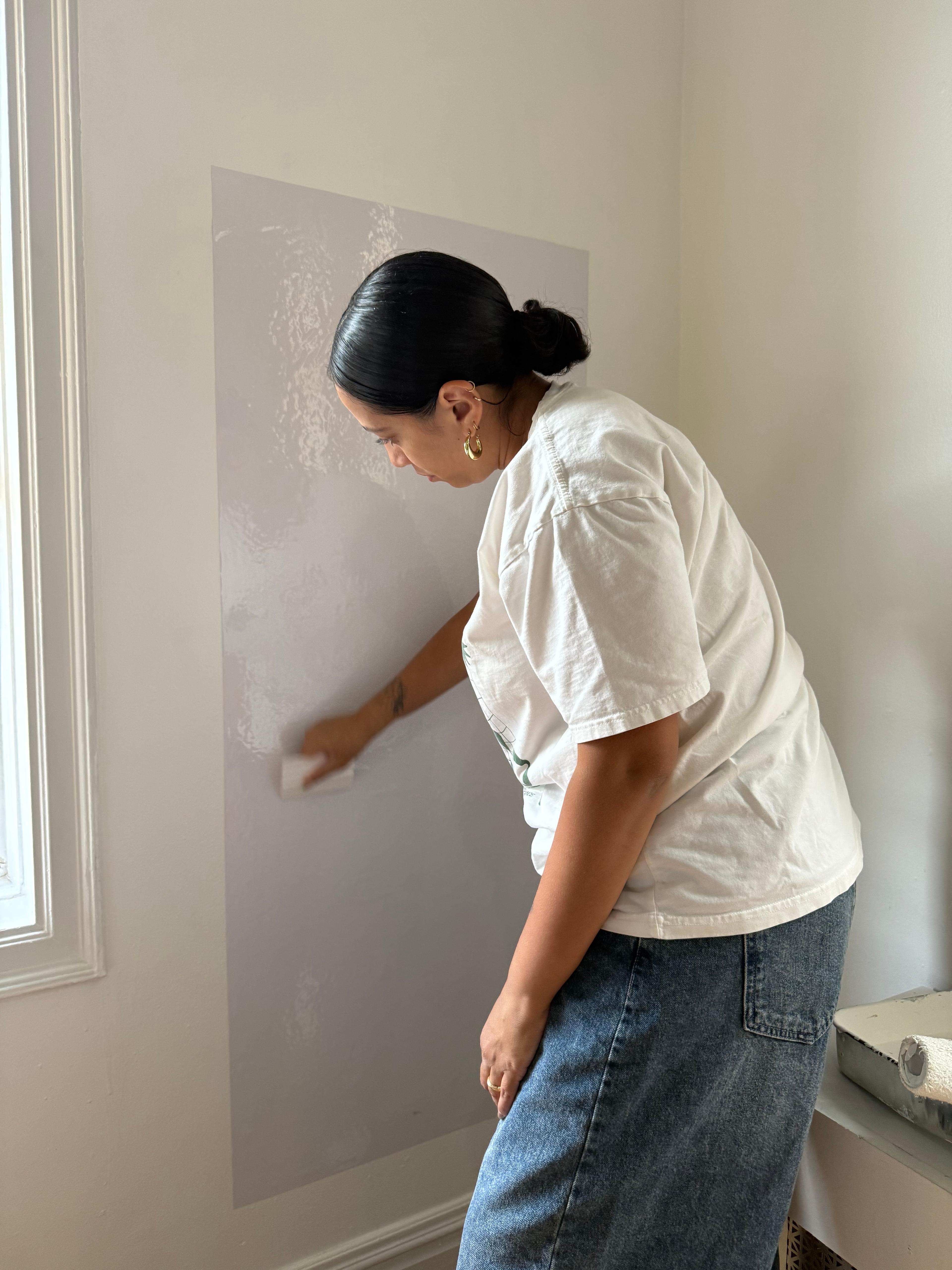 Applying a protective white vinyl sheet to the wall behind the art station.
