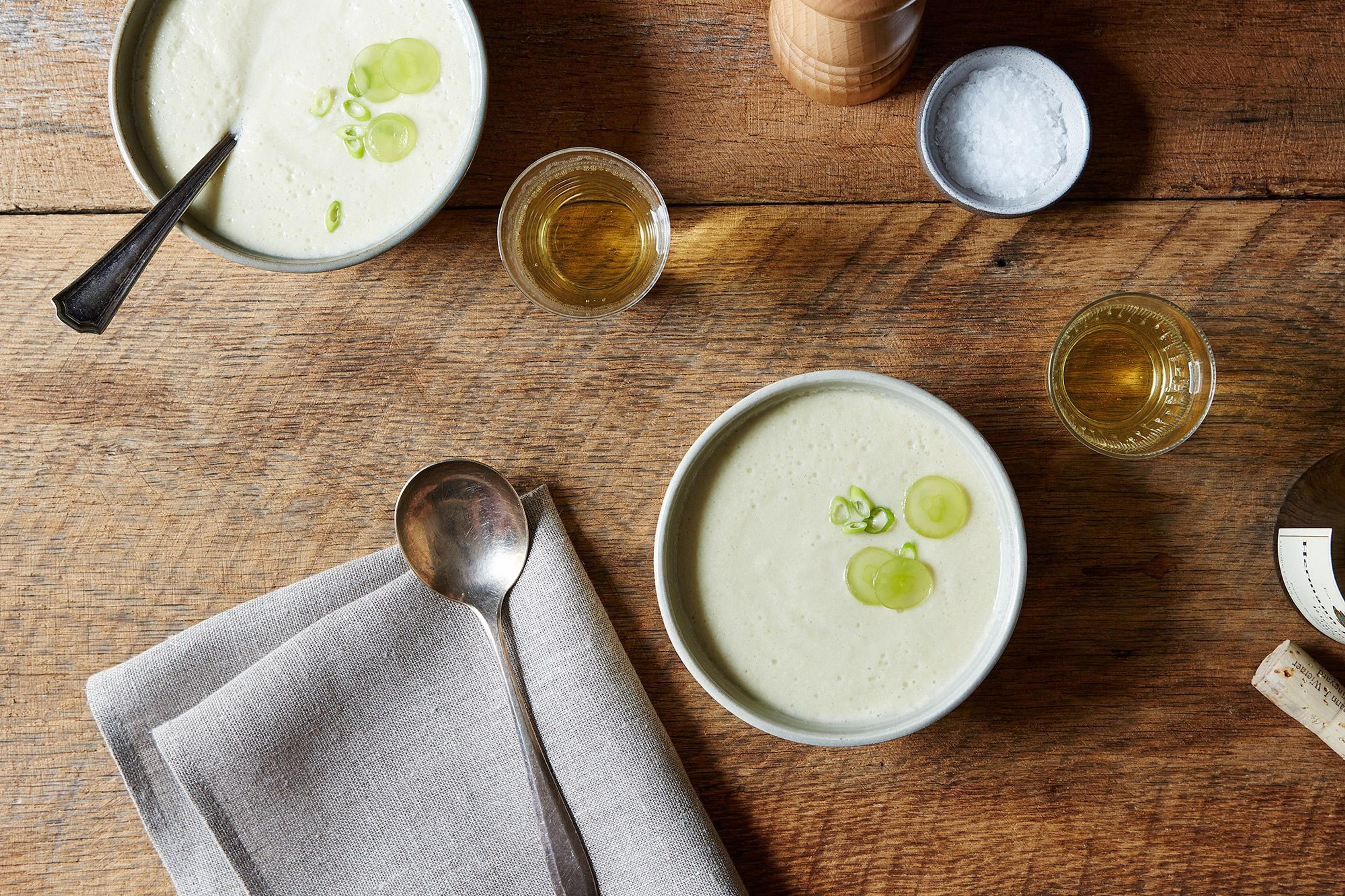 A top-down view of three bowls containing chilled gazpacho or cold soup garnished with herbs.