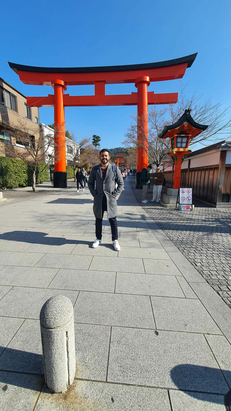A traditional large red wooden Torii gate in Japan under bright sunlight.