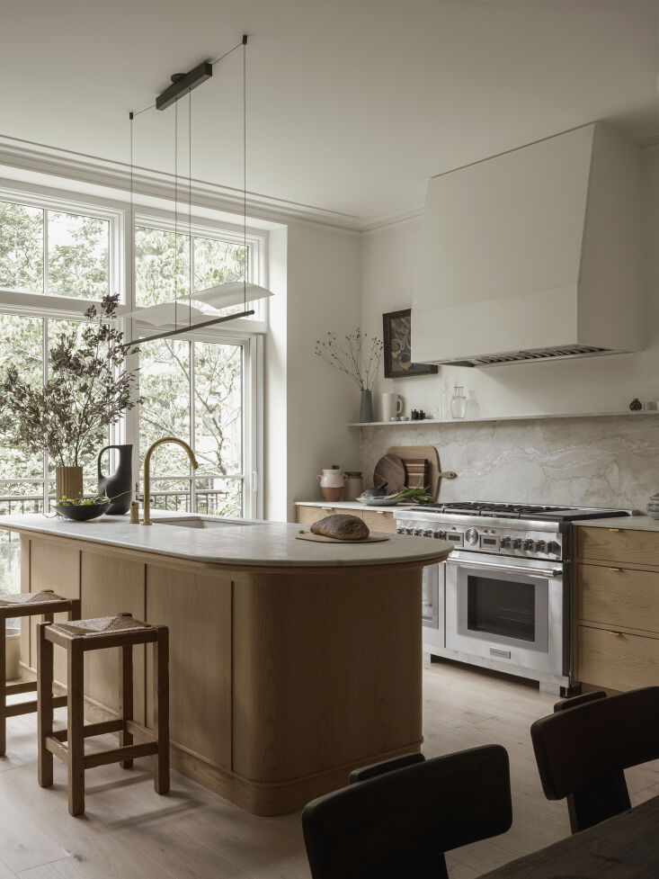 Kitchen island with curved Dolce Vita quartzite countertop looking toward a large window.