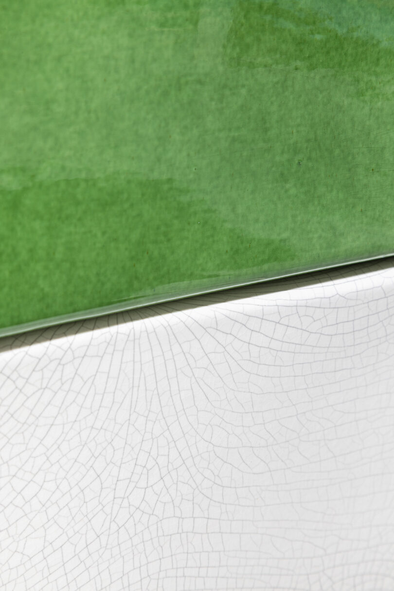 A macro view showing the contrast between a smooth green ceramic surface and a textured white crackle glaze.