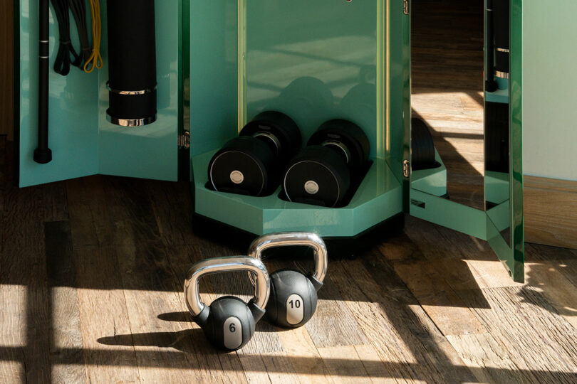 Close-up of Technogym dumbbells and kettlebells inside the Ottagono storage unit.