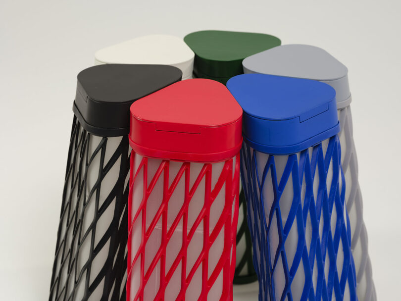 A circle of six Elio water bottles in various colors showing their diamond-patterned mesh design.