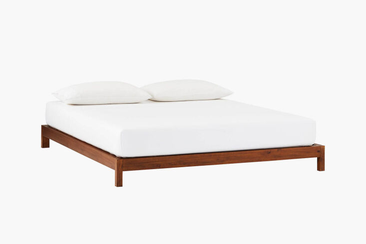 A CB2 Simple Acacia wood platform bed with a dark finish.