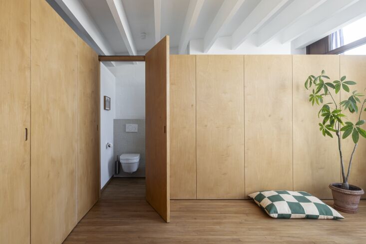 A bright upper floor with 'invisible' doors and partitions that stop short of the ceiling to allow light flow.