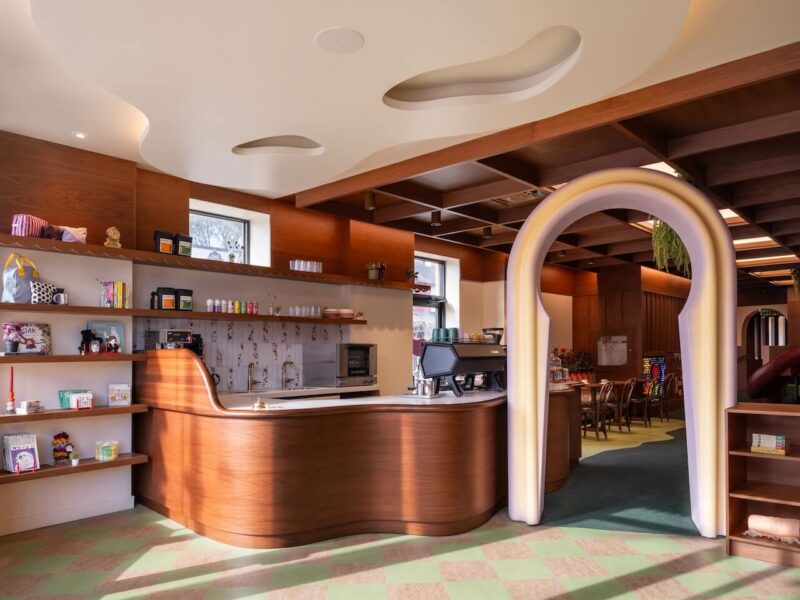 Modern cafe interior with clean wooden lines, a coffee counter, and a decorative archway.
