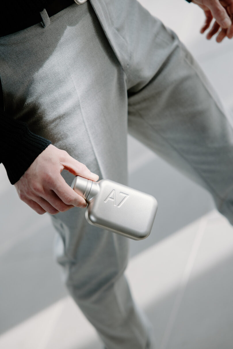 A hand holding the small, rectangular A7 Satin Steel memobottle.