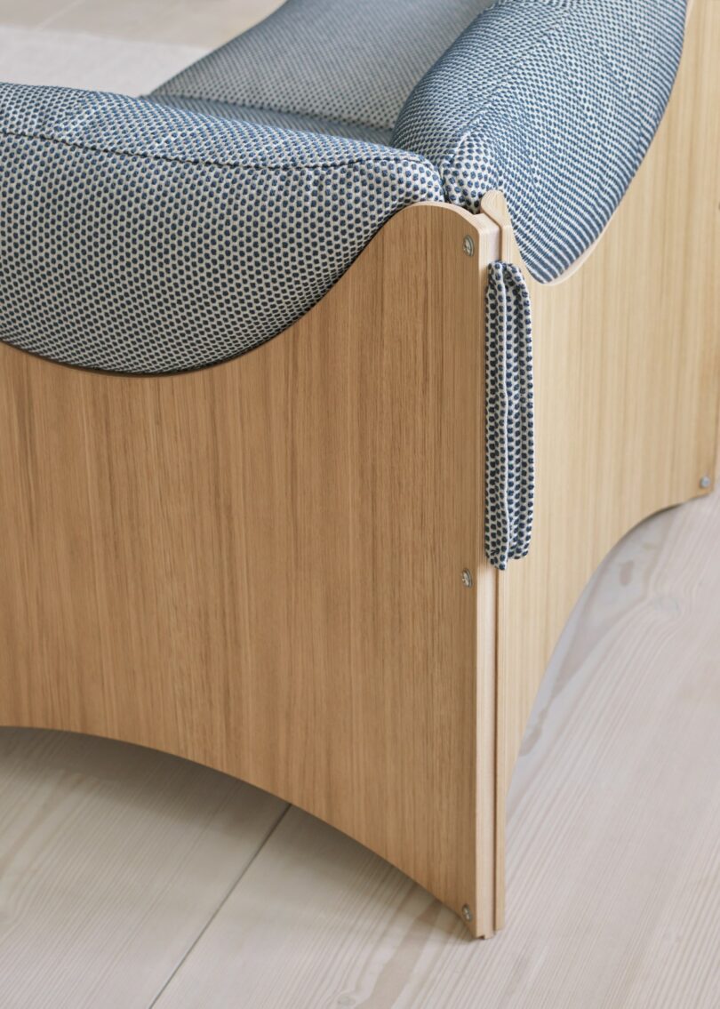 Close-up of high-quality blue upholstery fabric and light wood paneling on a modern chair.