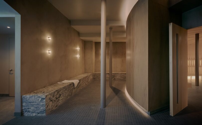 Minimalist spa interior with curved wooden walls and stone benches.