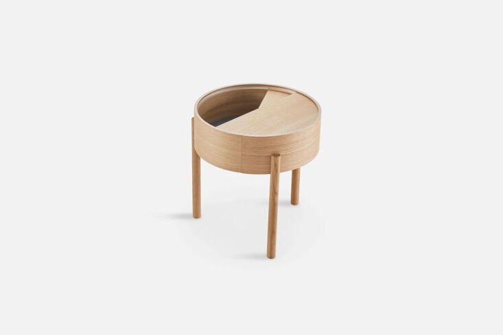 A round oak side table with a top that rotates to reveal a deep inner storage compartment.