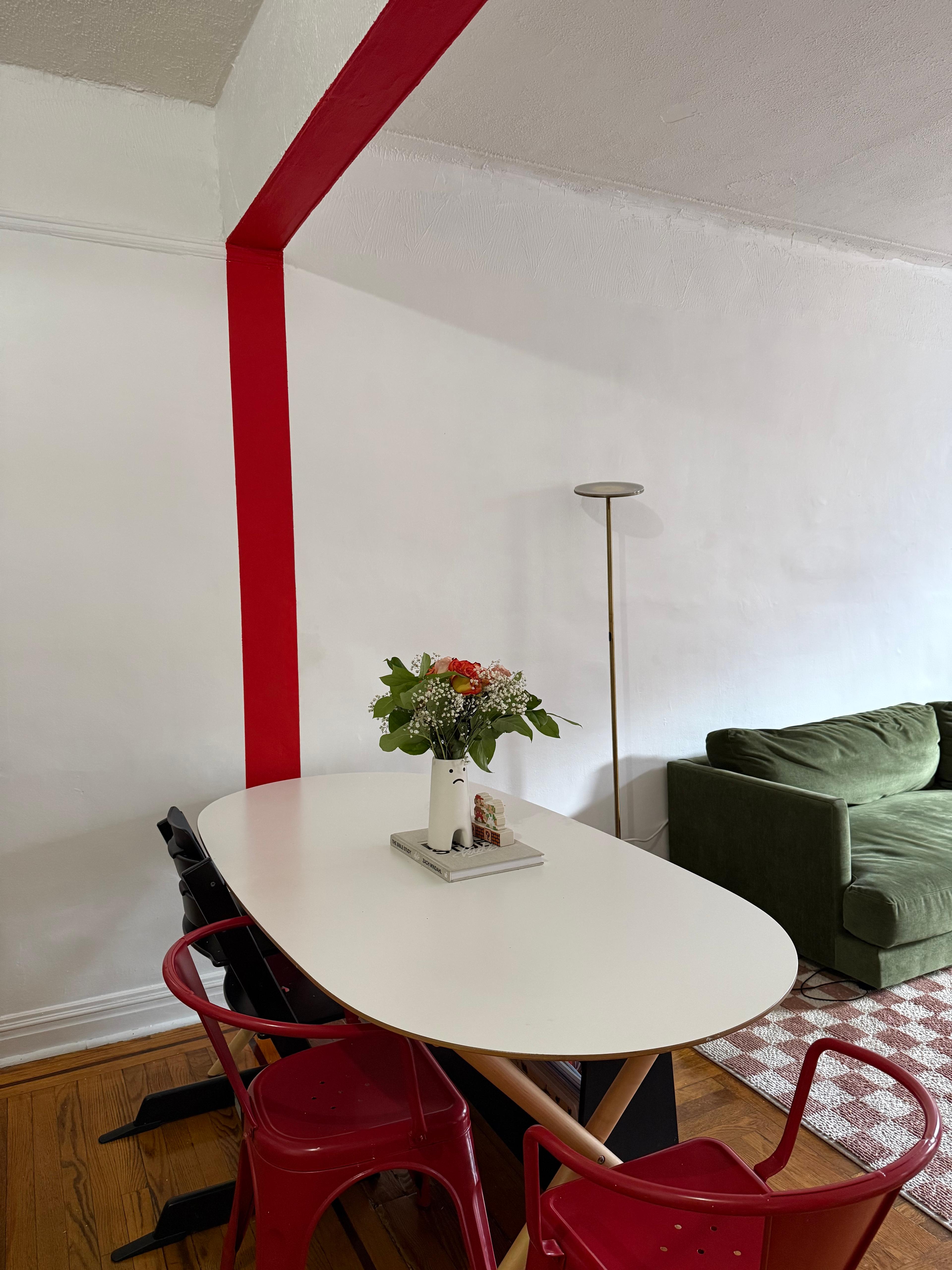 A bold red horizontal stripe painted across a white dining room wall with sharp edges.