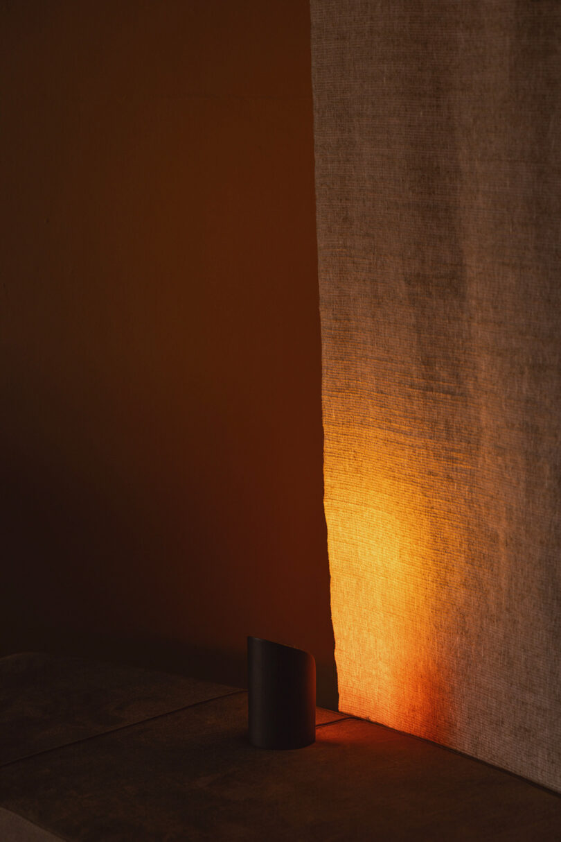 Warm orange ambient light illuminating a beige fabric curtain and a nearby surface.