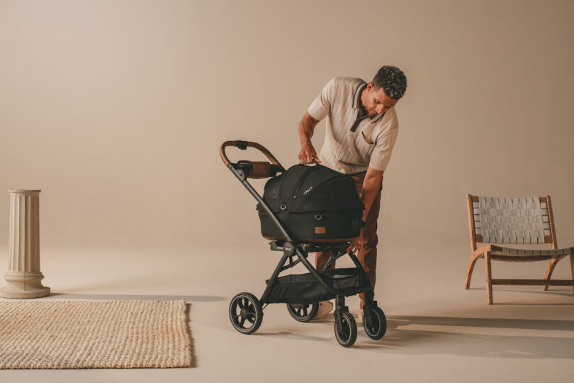 A person adjusting the attachment points of the Maeve carrier onto the stroller frame.