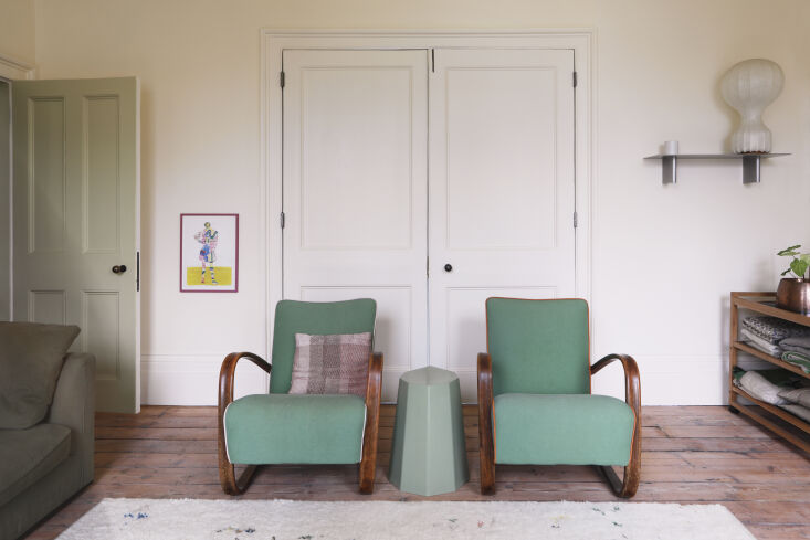 A pair of Jindrich Halabala chairs reupholstered in green fabric inside a historic home.