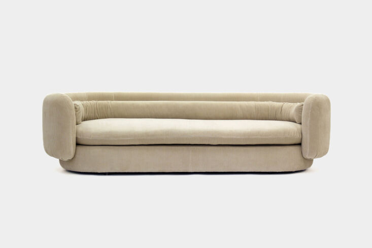 A sculptural half-seat sofa in purple corduroy fabric.