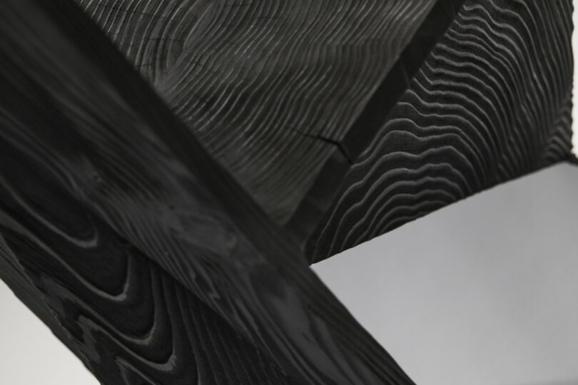 Close-up of black wooden beams meeting at sharp angles with visible wood grain patterns.
