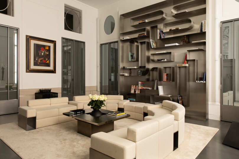 Modern living room featuring cream modular sofas and a distinctive geometric metal bookshelf filled with books.