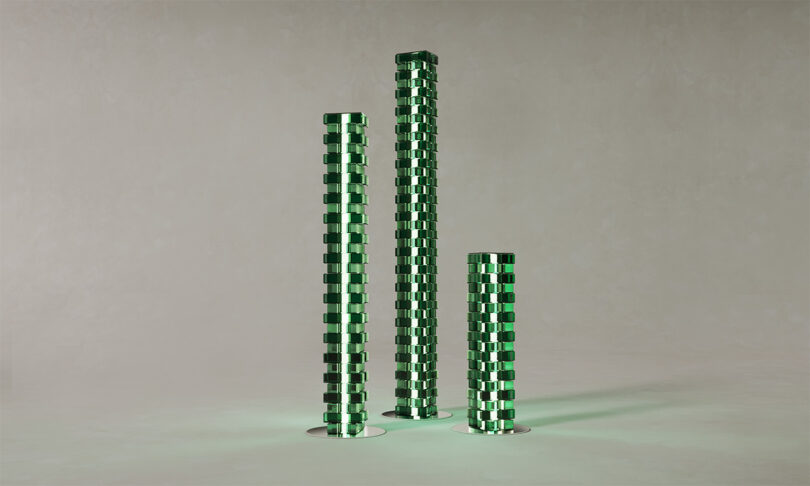 Three green glass-block lamps standing on a light-colored surface.