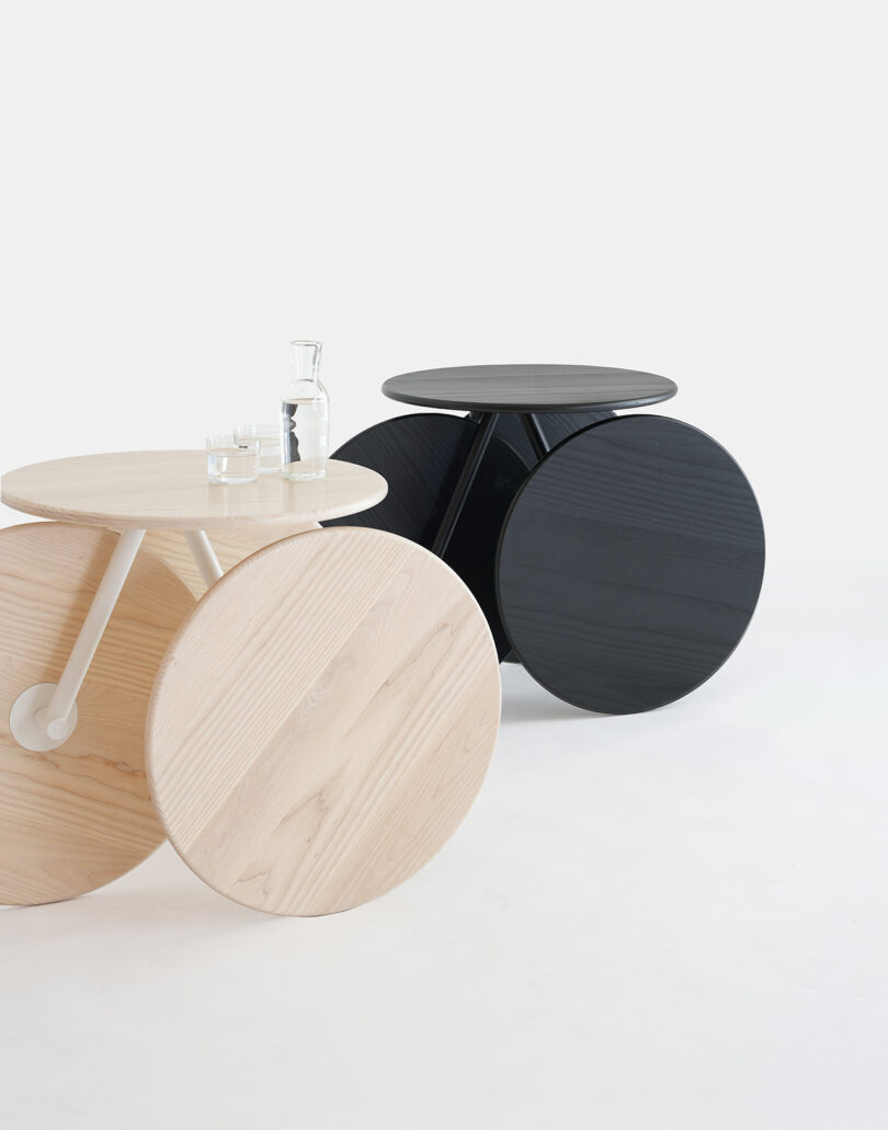Two round Rolly tables in light birch and black finishes side-by-side.