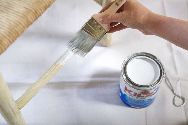 A chair being painted with a white base coat of primer.