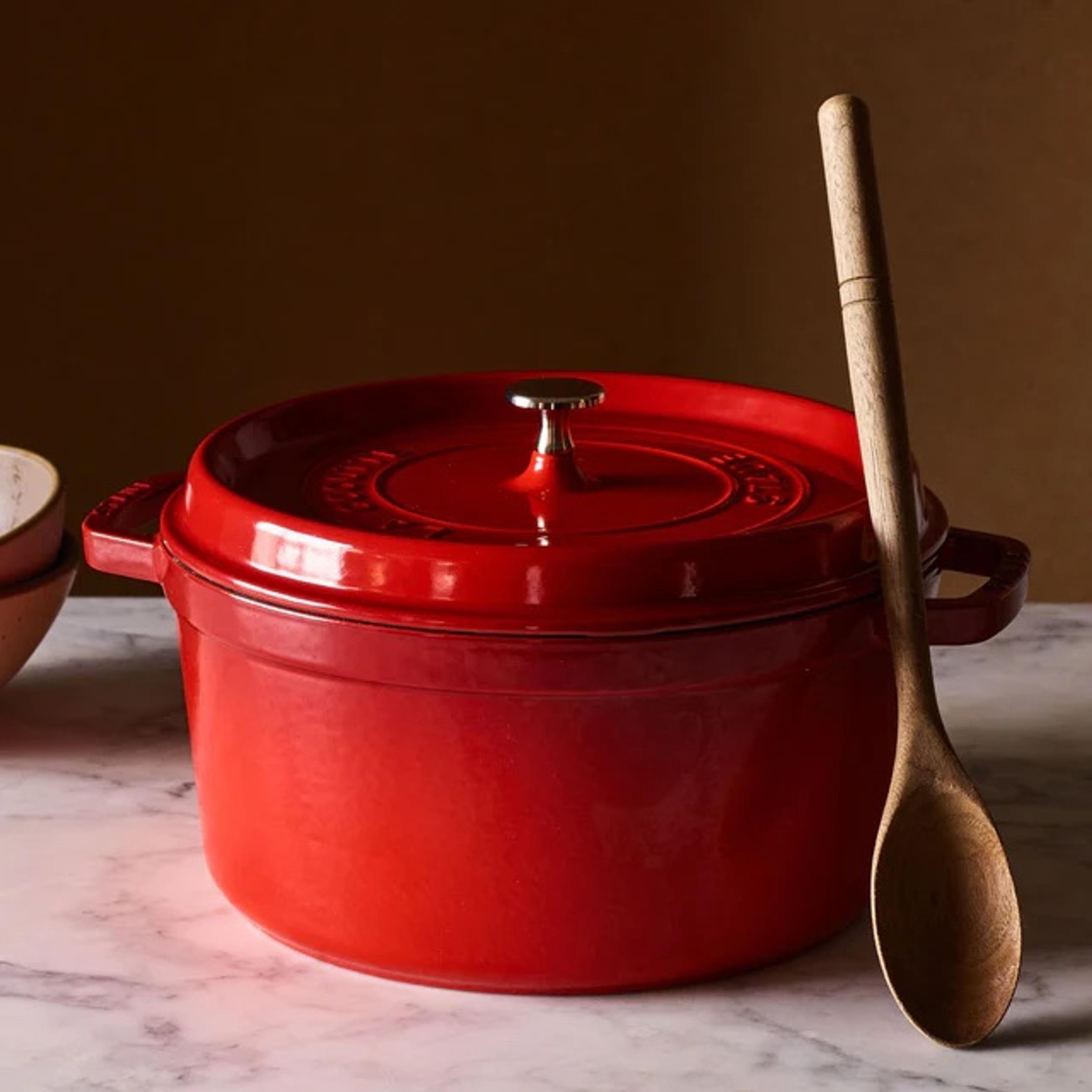 A red round Staub cast iron cocotte on a table setting.