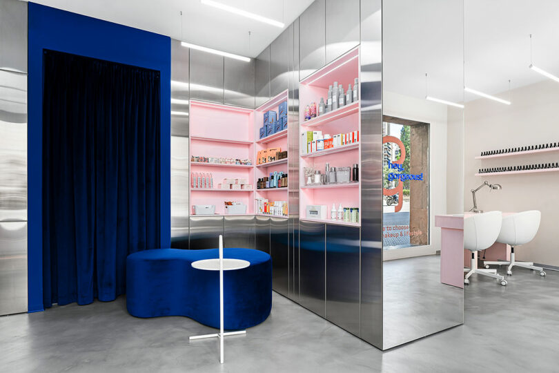 A wide shot of a modern beauty salon showing metallic walls, product displays, and service stations.