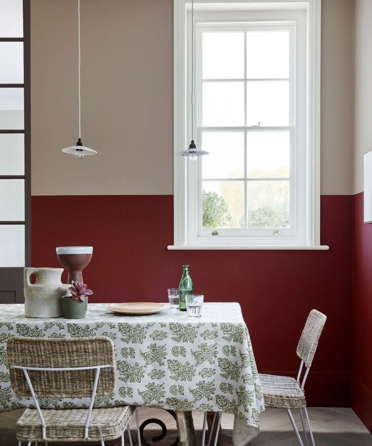 A two-toned kitchen featuring deep red cabinets on one side and warm gray-beige cabinets on the other.