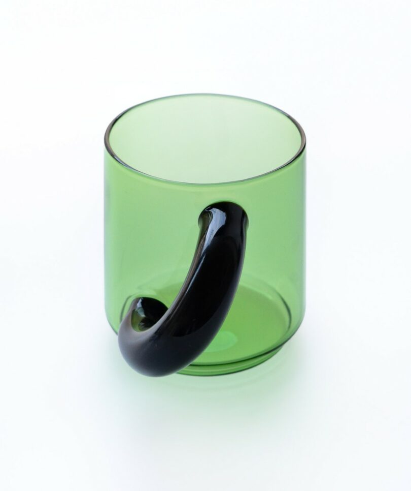 A translucent green glass mug with a thick, curved black handle.