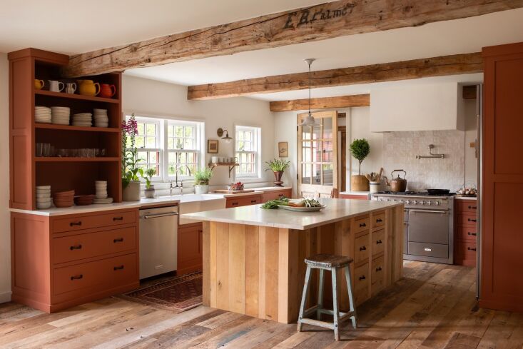 Kitchen featuring custom terracotta-colored cabinets, a central island, and a classic Aga range.