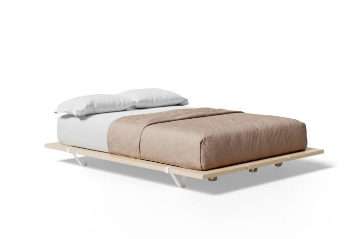 A low-profile wooden bed frame without a headboard in a clean, white-walled room.