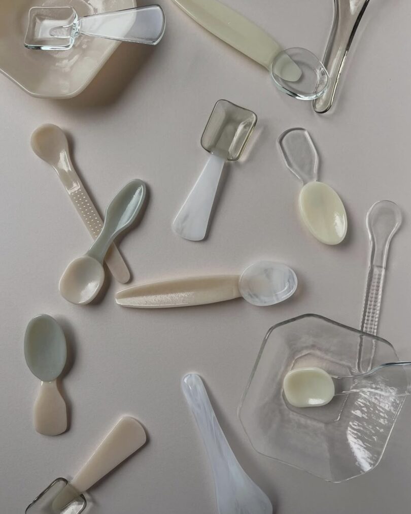 Close-up of translucent and opaque hand-blown glass objects on a beige surface.