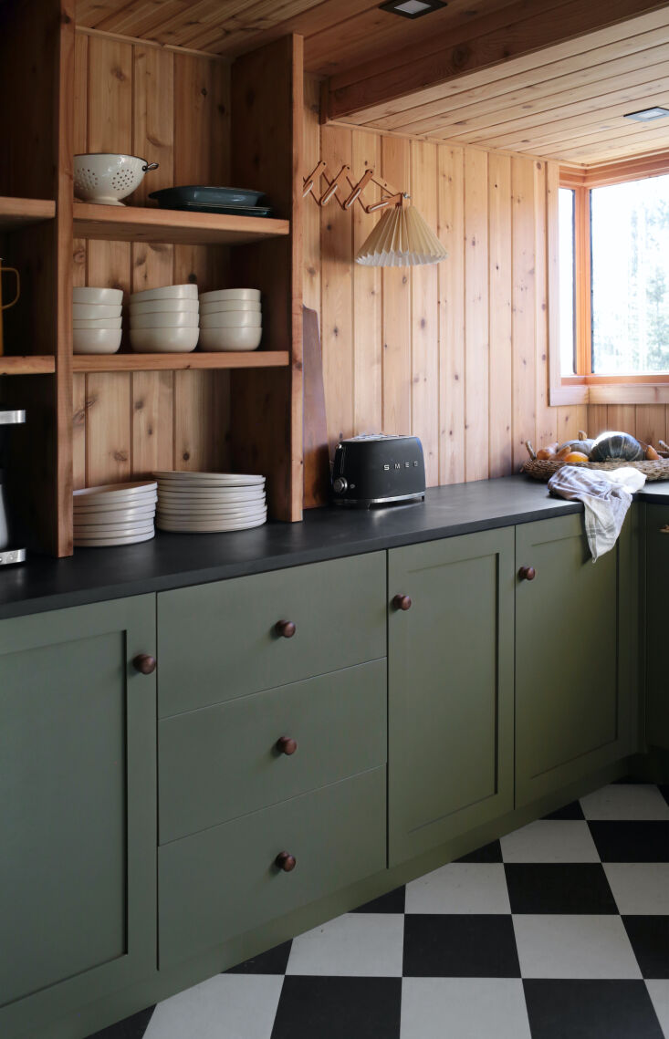 Open wooden shelves with stoneware dishes and a brass accordion wall light.
