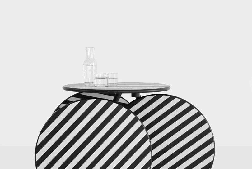 A Rolly table with black and white diagonal stripes holding a glass of water.