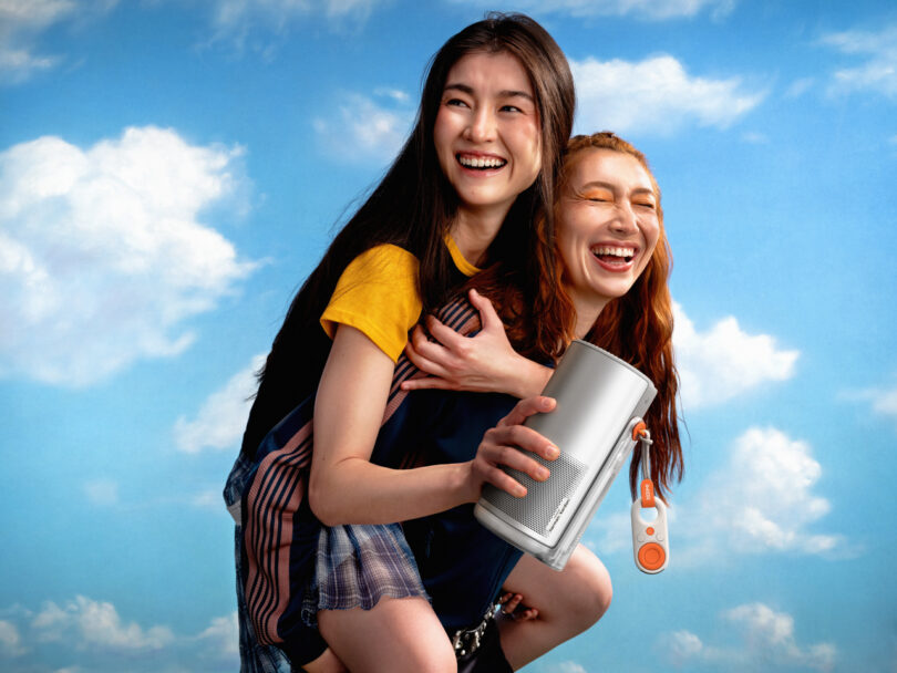 Two women laughing and holding the XGIMI MoGo 4 projector outdoors.