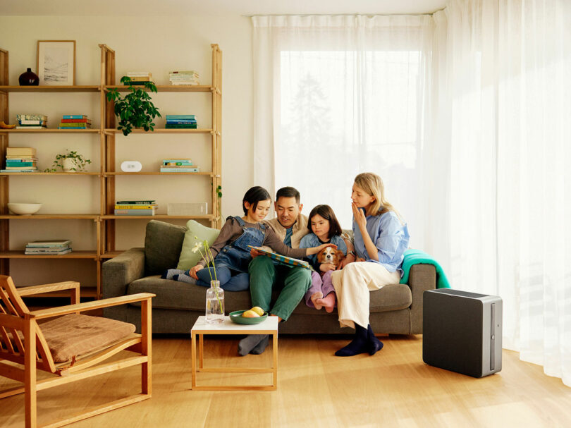 A family of four sitting on a couch in a cozy living room reading together.