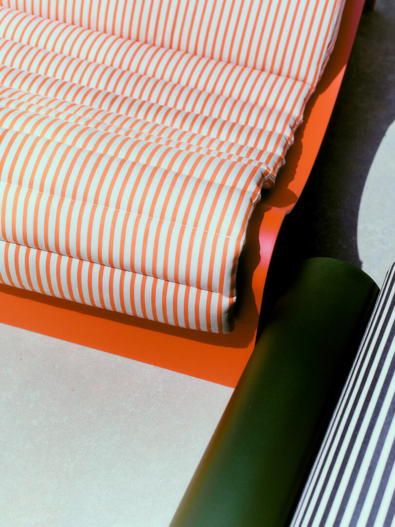 Close-up of rolled orange and white striped fabric next to a dark green cylindrical object.