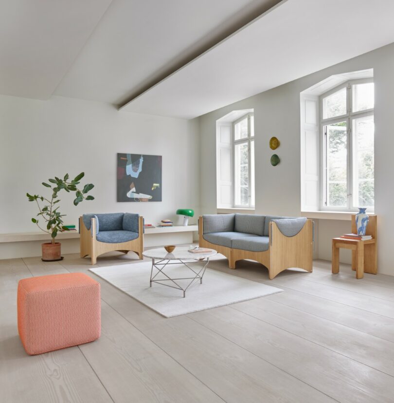 A bright, minimalist living room with modern wooden furniture and large windows.