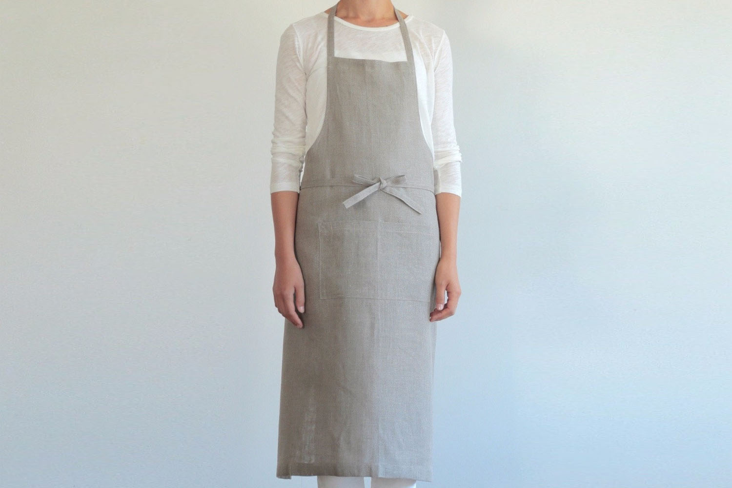 A minimalist light-colored linen apron with a simple stamped logo.