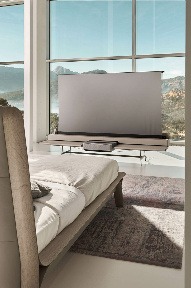 A modern bedroom featuring a retractable screen appearing from a console at the foot of the bed.